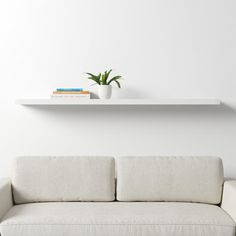 a white couch sitting under a floating shelf