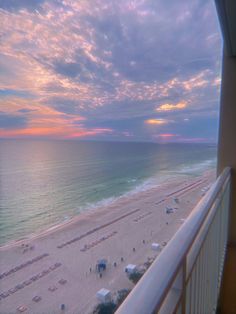 an aerial view of the beach and ocean at sunset from a balcony in a hotel room