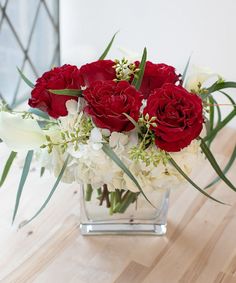 a glass vase filled with red and white flowers