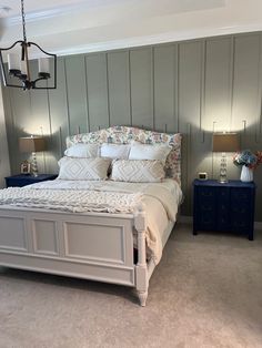 a bedroom with a bed, nightstands and two lamps on either side of the bed