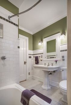 a bathroom with green walls and white fixtures