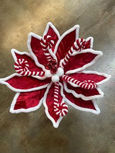 a red and white poinsettia with candy canes on it's center