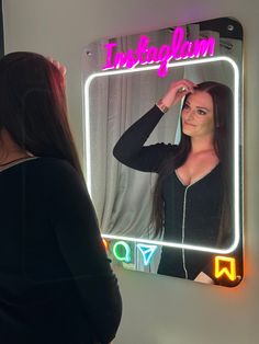 a woman standing in front of a mirror looking at her reflection with the word instagram on it