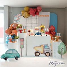 an assortment of balloons and decorations in a room with a toy car on the floor