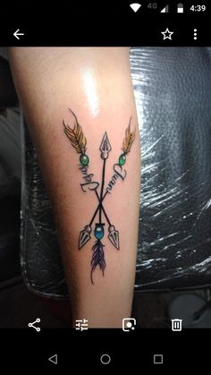 an arrow tattoo on the arm with some arrows and feathers around it, in black and white