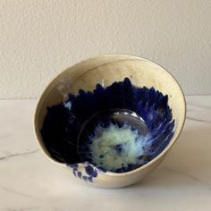 a blue and white bowl sitting on top of a marble counter next to a wall