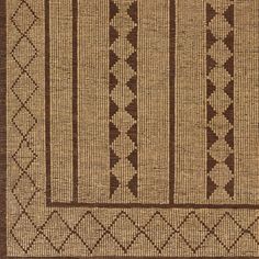 a brown and white rug with geometric designs on the front, in an area that is very