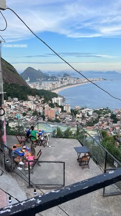 an outdoor dining area overlooking the ocean and cityscape with mountains in the background