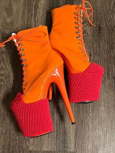 a pair of orange and red high heeled boots on top of a wooden floor