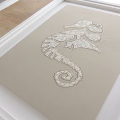 an intricately designed artwork is displayed in a white frame on the floor next to a window