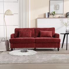 a red couch sitting on top of a white rug