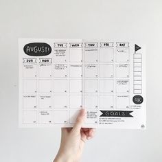 a person holding up a planner with the words august on it and arrows pointing in different directions