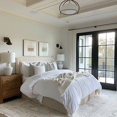 a large white bed sitting in a bedroom next to a sliding glass door with french doors