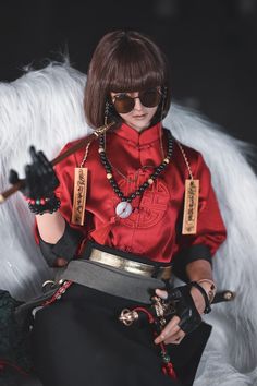 a woman in red shirt and black skirt sitting on a white chair with her hand up