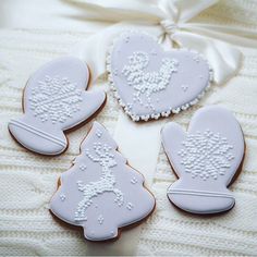 three decorated cookies sitting on top of a white blanket