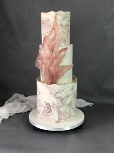 a three tiered cake with pink and white frosting on it's side