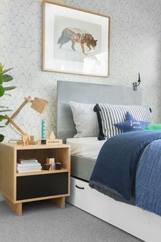 a bed room with a neatly made bed next to a night stand and a plant