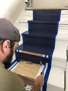 a man is painting stairs with blue tape and white paint on the bottom half of them