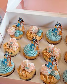 a box filled with cupcakes covered in blue frosting and topped with cats