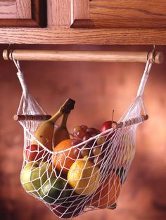 a fruit basket hanging from a wooden shelf