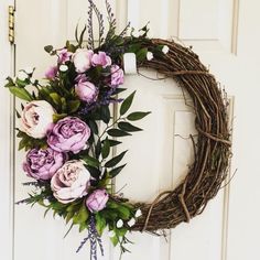 a wreath with purple flowers hanging on the front door to welcome someone who has passed it