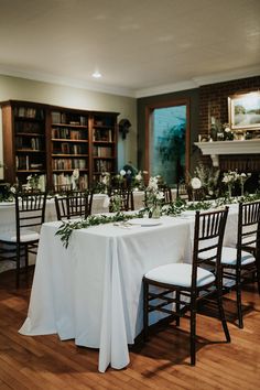 the table is set up with white linens and greenery for an elegant wedding reception