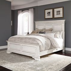 a white bed sitting in a bedroom on top of a hard wood floor next to a window