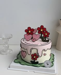 a decorated cake with flowers and hearts on the top is sitting on a white table