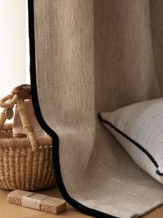 a wicker basket sitting next to a window with a pillow on top of it