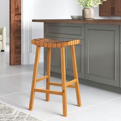 a wooden stool sitting in the middle of a kitchen next to a counter with flowers on it