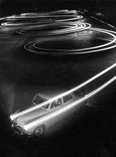 an old car is parked in the parking lot at night with light streaks on it