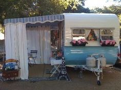 an old camper converted into a house with flowers in the window boxes and curtains