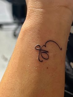 a woman's wrist with a small tattoo design on the left side of her arm