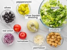 the ingredients for this salad include lettuce, olives, tomatoes, red onion, and peppers