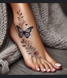 a woman's foot with a butterfly and flowers tattoo on the bottom of it