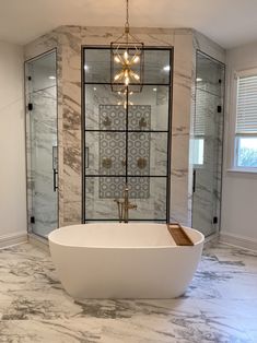 a large bathroom with marble floors and walls, including a freestanding tub in the center