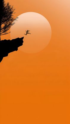 the silhouette of a person jumping into the air from a cliff in front of an orange sky