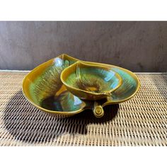 two yellow and green bowls sitting on top of a wicker tablecloth covered floor