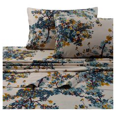 a bed with blue and yellow flowers on the comforter, sheets and pillow cases