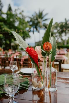 two vases with flowers are sitting on a table in the middle of an outdoor dining area