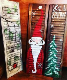 three wooden shutters decorated with christmas decorations and santa clause painted on the front door