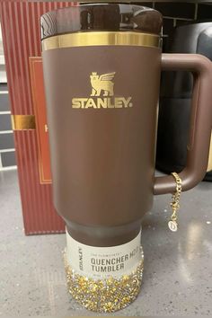 a coffee mug with gold trimmings and a chain on the handle is sitting on a counter