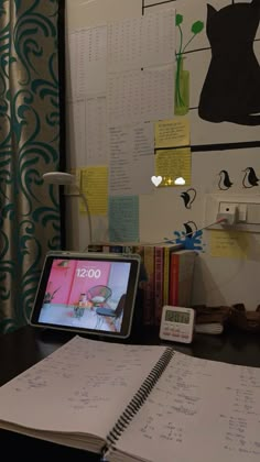 an open notebook sitting on top of a desk next to a calculator and clock