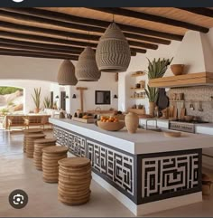 an open kitchen with lots of counter space and wicker baskets hanging from the ceiling