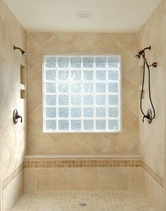 a bathroom with tiled walls and flooring next to a window in the shower area