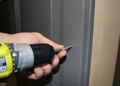 a person is holding a drill and screwdriver in their hand while opening the door