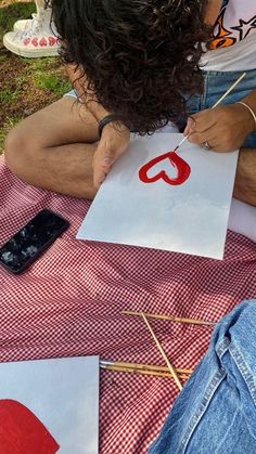 a woman sitting on top of a red and white checkered table cloth holding a piece of paper