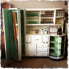 an old fashioned kitchen with green and white cupboards, drawers, and other items