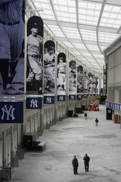 two people are walking in an indoor baseball stadium with banners on the wall and ceiling