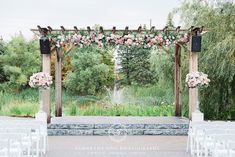 an outdoor wedding ceremony setup with white chairs and pink flowers on the arbor, surrounded by greenery